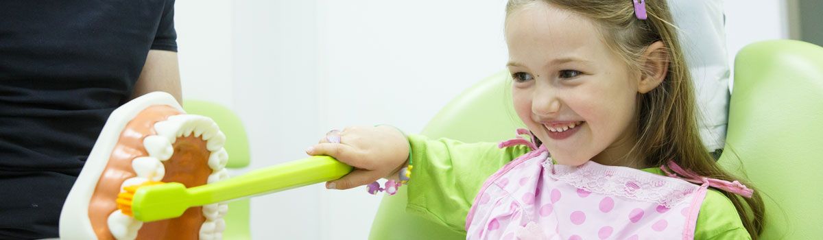 Young girl using teeth brushing model