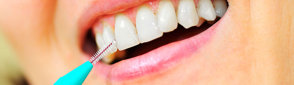 Woman cleaning teeth with thin brush