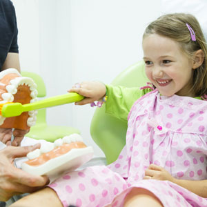 Young girl using teeth brushing model