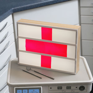 Emergency red cross symbol on illuminated board in dental treatment room