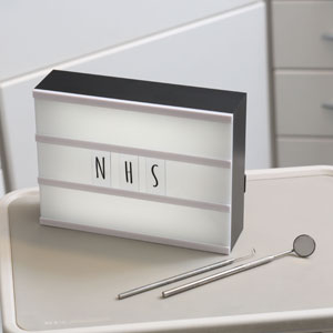‘NHS’ on illuminated board in dental treatment room