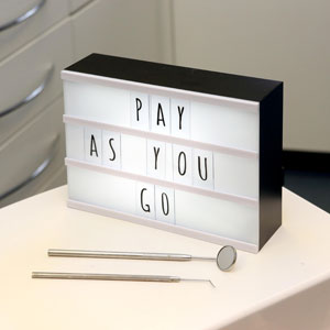 ‘Pay As You Go’ on illuminated board in dental treatment room